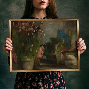 May include: A rectangular painting in a thin gold frame featuring an impressionistic scene of potted plants with muted green, brown, and pink tones, alongside a prominent blue floral element, all rendered with visible, textured brushstrokes.