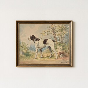 May include: A framed painting of a white and brown spotted pointer dog standing in a wooded landscape. The dog wears a collar and faces left. The artwork features muted earth tones and includes the signature A. Pope Jr. in the bottom right corner.