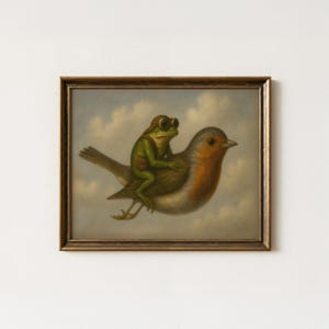 Pode incluir: Uma impressão de arte emoldurada apresentando um sapo verde usando óculos de aviador castanhos e uma pequena bolsa, montado nas costas de um pisco-de-peito-ruivo. A cena é definida contra um céu nublado, dentro de uma moldura de madeira castanha.