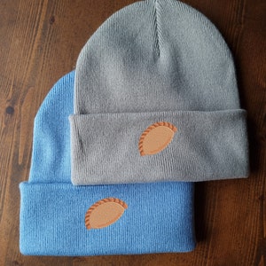 May include: Two knit beanies, one gray and one blue, with a brown pastry design embroidered on each.
