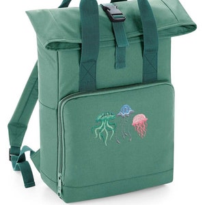May include: A green canvas backpack with a roll-top closure and a buckle. The backpack has a front pocket with an embroidered design of three jellyfish in different colors.