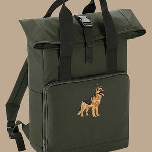 May include: Dark green backpack with a roll-top closure and a front zipped pocket. The backpack features a German Shepherd embroidery on the front. It has adjustable shoulder straps and a top handle. The buckle is black.