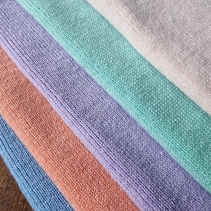 May include: Five fabric swatches in different colors: light pink, light green, lavender, peach, and light blue. The fabric has a soft, textured surface.