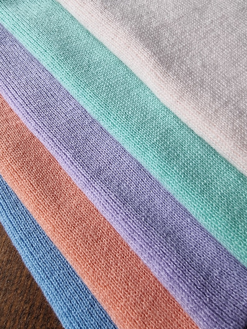 May include: Five fabric swatches in different colors: light pink, light green, lavender, peach, and light blue. The fabric has a soft, textured surface.