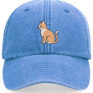May include: A light blue baseball cap with an embroidered design of a seated orange and white cat. The cap has a curved peak and an adjustable strap at the back. The cat illustration is detailed and centered on the front of the cap.
