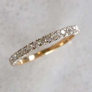May include: A delicate gold band with a row of small, sparkling diamonds set in a pave setting.