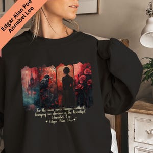 Puede incluir: Sudadera negra con un dise&ntilde;o literario. El gr&aacute;fico presenta un cuervo, una silueta y rosas rojas, con texto del poema "Annabel Lee" de Edgar Allan Poe. La sudadera tiene cuello redondo y mangas largas.