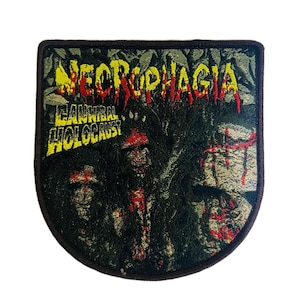 Puede incluir: Un parche con un borde verde oscuro. El diseño presenta el texto "NECROPHAGIA" en rojo y amarillo, con "CANNIBAL HOLOCAUST" debajo. La imagen incluye un gráfico de una escena de terror.