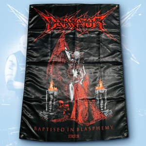May include: A black rectangular fabric wall banner featuring the red text "DESSICATOR" at the top and "BAPTISED IN BLASPHEMY" at the bottom. The central graphic depicts a horned figure with wings standing between two flaming stone pillars.