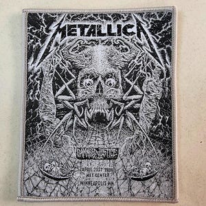 May include: A rectangular Metallica patch in black and white, displaying a skull and crossbones graphic. The band's name is at the top, with "...And Justice for All" and tour details at the bottom, including "April 21st 1989, Met Center, Minneapolis MN."