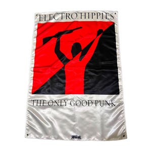 May include: A satin flag with the text "ELECTRO HIPPIES" and "THE ONLY GOOD PUNK..." in white. The flag features a red and black graphic of a person holding a rifle and raising a fist.