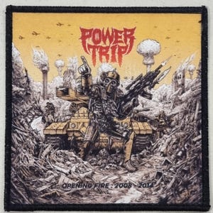 Peut inclure: Écusson carré à bordure noire. L'image représente un soldat avec un masque à gaz et une arme, dans un paysage ravagé par la guerre. Le texte "POWER TRIP" est en haut, avec "OPENING FIRE: 2008-2014" en bas, dans une illustration détaillée.