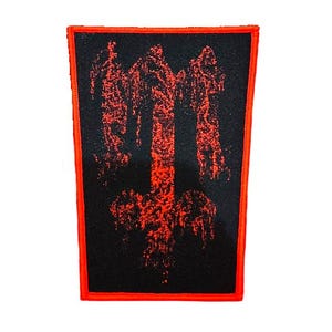 Può includere: Toppa rettangolare nera con un disegno a croce rovesciata rossa. La toppa ha un bordo rosso e un aspetto strutturato. Il design è in stile grunge.
