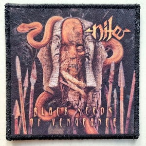 Op de afbeelding: Vierkante patch met een zwarte rand met een gedetailleerde illustratie. Het kunstwerk bevat een centraal figuur met een slang, speren en de bandnaam "Nile" in een gestileerd lettertype. De tekst "BLACK SEEDS OF VENGEANCE" is ook aanwezig.