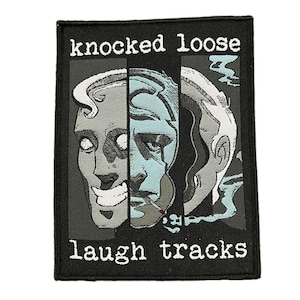 May include: Black rectangular patch with the words "knocked loose" and "laugh tracks" in white. The patch features a graphic of a face split into three sections, with blue and gray tones.