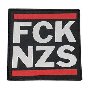 Może przedstawiać: Kwadratowa czarna naszywka z białymi literami blokowymi, które piszą "FCK NZS" nad i pod czerwonym paskiem. Naszywka ma czarną obwódkę.