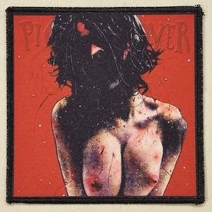 Può includere: Toppa quadrata con bordo nero con un'illustrazione stilizzata di una persona con capelli scuri su sfondo rosso. La parola "PILLOVER" è stampata in rosso nella parte superiore.