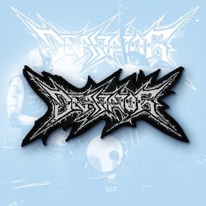 May include: A black and white embroidered patch featuring the word DEVASTATOR in a jagged, stylised metal font. The design has sharp, pointed edges and a high-contrast aesthetic, with white lettering outlined in black thread on a fabric base.