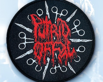 May include: A round black patch with the words "BURD OFF" in red, stylized, dripping font. White scissors and knives surround the text, creating a circular design. The patch is likely for clothing or accessories.