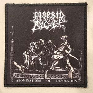 May include: Black square patch featuring the band name "MORBID ANGEL" in white, stylized lettering. Below, a graphic depicts skeletal figures. The text "ABOMINATIONS OF DESOLATION" is at the bottom. The patch has a black border.