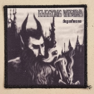 Könnte beinhalten: Schwarz-weißer Aufnäher mit dem Text "ELECTRIC WIZARD" und "dopethrone". Das Bild zeigt eine gehörnte Figur und eine Stadtsilhouette. Der Aufnäher hat einen schwarzen Rand.