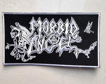 May include: A black embroidered patch with white stitching. The patch features the text "MORBID ANGEL" in a gothic font with a winged demon figure and a pentagram.