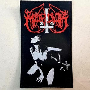 Puede incluir: Parche rectangular negro con un logotipo rojo estilizado y una cruz invertida blanca con el número 6. Debajo, una ilustración en blanco y negro de una figura desnuda. El parche es probablemente para ropa o accesorios.