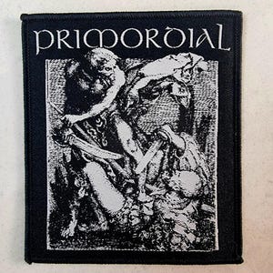 May include: Black and white embroidered patch with the band name "PRIMORDIAL" in white lettering. The patch features a graphic of two figures in a dramatic pose.