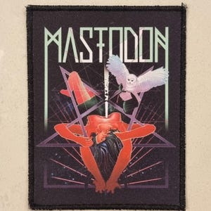 May include: Black patch featuring the band name "MASTODON" in a stylized font. The graphic includes a figure in a pentagram, an owl, and geometric lines, all in shades of red, green, and purple. The patch has a black border.