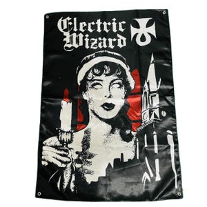 May include: Black banner with the words "Electric Wizard" in white gothic lettering. The banner features a black and white illustration of a woman holding a candle, with a church and cityscape in the background.