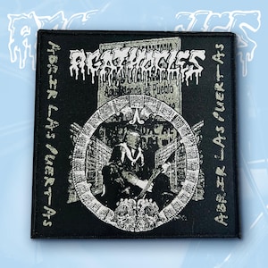 May include: A square black embroidered patch featuring the white text AGATHOCLES at the top and ABRIR LAS PUERTAS vertically on both sides. The center displays a circular frame enclosing a monochromatic illustration of a figure holding a rifle.