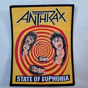May include: A yellow and red woven patch with the band name "Anthrax" and the album title "State of Euphoria" printed in black.