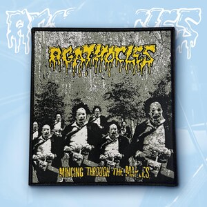 May include: A rectangular embroidered patch featuring a black and white graphic of multiple figures wearing masks and holding chainsaws. The text AGATHOCLES appears in yellow with a dripping effect at the top, and MINCING THROUGH THE MAPLES in yellow at the bottom.