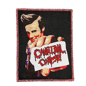 Op de afbeelding: Geborduurde patch met een zwarte achtergrond en rode rand. Het toont een persoon die een bord vasthoudt met de woorden "CANNIBAL CORPSE" in druipende rode letters. De afbeelding is gestileerd.