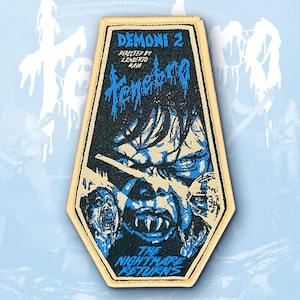 Puede incluir: Un parche rectangular con borde beige y fondo negro. El parche presenta el texto "DEMONI 2" y "Tenebra" en azul, junto con un gráfico de la cara de un monstruo y el texto "THE NIGHTMARE RETURNS".