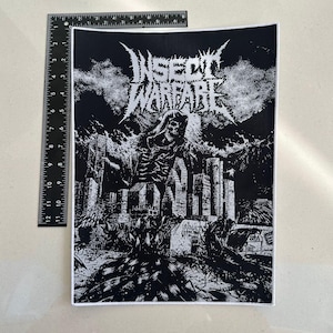 May include: Black and white patch with the band name "INSECT WARFARE". The graphic shows a skeletal figure in a city. The patch is approximately 30 cm high and 20 cm wide. The patch has a white border.