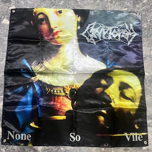 May include: A black flag with a classical painting of a woman and a skull, and the text "CRYPTOSY" in a white, gothic font. The words "None So Vile" are printed at the bottom in white. The flag has grommets in the corners.