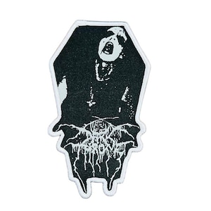 Puede incluir: Parche en blanco y negro con forma de ataúd. Presenta una figura gritando y la palabra "THROVE" en una fuente estilizada. El parche tiene un borde blanco y está diseñado para adherirse a ropa o accesorios.