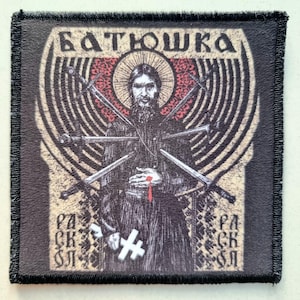 May include: Square patch with a black border featuring an illustration of a bearded figure surrounded by swords. The text "БАТЮШКА" is at the top, with additional Cyrillic text and a cross at the bottom. The design has a vintage, religious theme.