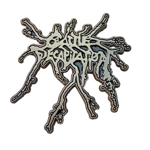 May include: A silver-colored metal pin with the word "DECAPITATED" in a stylized, dripping font. The pin has a complex, organic shape with multiple tendrils and a dark gray fill. The design is set against a white background.