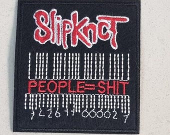 May include: Black square patch with the band name "Slipknot" in red, stylized lettering. Below, a barcode design and the phrase "PEOPLE=SHIT" in red. White embroidered details and numbers complete the design.