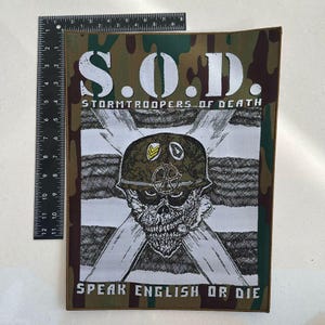 May include: A rectangular patch with a camouflage border and the text "S.O.D. STORMTROOPERS OF DEATH SPEAK ENGLISH OR DIE." The central image features a skull wearing a military helmet, set against a backdrop of crossed white stripes.