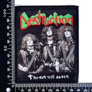 Op de afbeelding: Zwart-wit geborduurde patch met de bandnaam "Destruction" in rode en groene letters. De tekst "Thrash 'till death" staat onder de bandnaam.