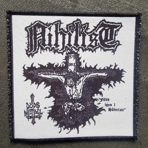 May include: A square, white patch with a black border featuring the word "Aihilist" in gothic lettering above a depiction of a crucified figure. Below the figure are the words "Döds Metall" and "Född igen i Händelse".