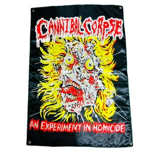 Puede incluir: Bandera negra con el nombre de la banda "CANNIBAL CORPSE" en rojo, sobre una cara grotesca, gritando, con pelo amarillo y acentos rojos. El texto "AN EXPERIMENT IN HOMICIDE" está impreso en rojo en la parte inferior. La bandera tiene ojales en las esquinas.