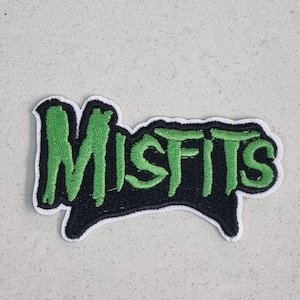 May include: Embroidered patch with the word "MISFITS" in green, stylized lettering. The text is set against a black background with a unique shape and a white border. Suitable for jackets, bags, or other fabric items.