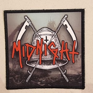 Puede incluir: Un parche cuadrado con borde negro presenta la palabra "MIDNIGHT" en letras rojas estilizadas. Dos hoces blancas se cruzan detrás de una forma de campana con una cruz. El fondo es una imagen en escala de grises de un edificio.