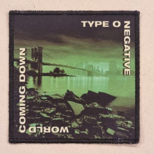 May include: Black square patch with the text "TYPE O NEGATIVE" and "COMING DOWN WORLD". The patch features a green-tinted image of a bridge over water with a rocky shoreline.