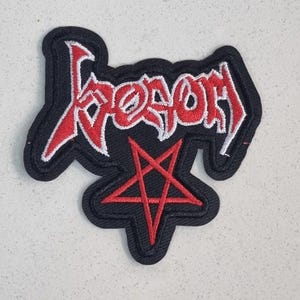 Op de afbeelding: Zwart geborduurde patch met het woord "Venom" in het rood, met een witte omlijning. Een rode pentagram staat onder het woord. De patch heeft een zwarte rand.