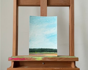 Small hand painted landscape on A4 paper with a green miniature chair and blue sky